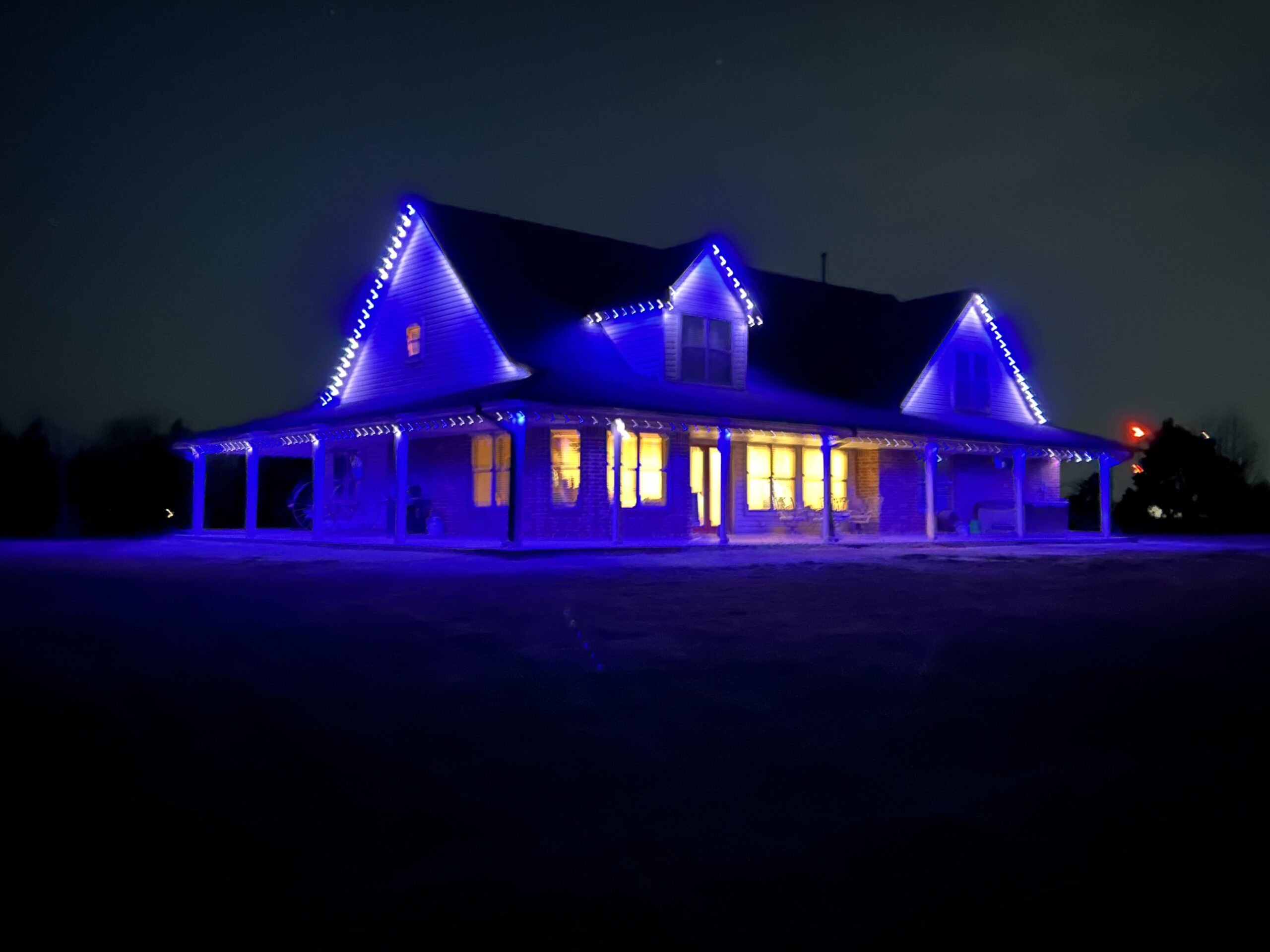 Large home glowing with blue and white smart lighting at night, showcasing customizable app-controlled LED effects